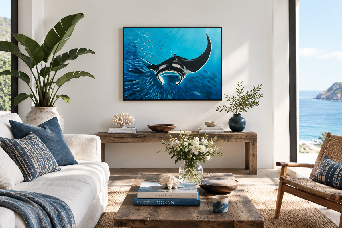 A framed wall art print depicting a manta ray swimming in a bright blue ocean, displayed in a modern, sunlit living room above a wooden console table.